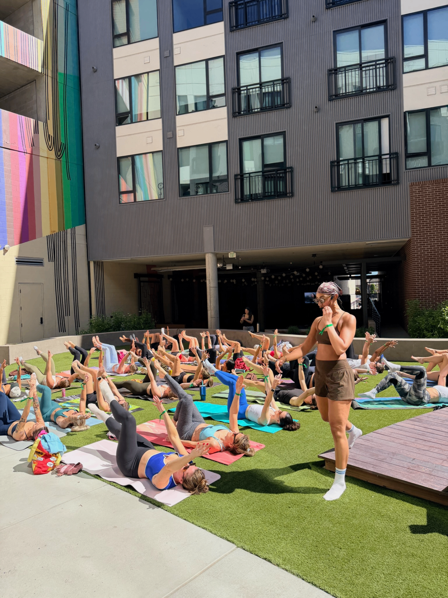 Outdoor courtyard pilates class led by an instructor on a sunny day